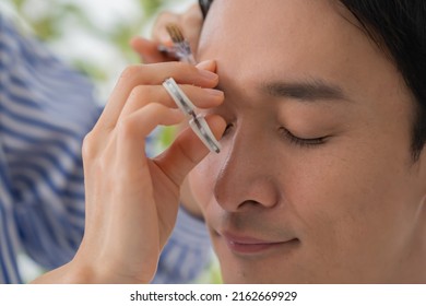 Cosmetologist And Japanese Man Trimming Eyebrows
