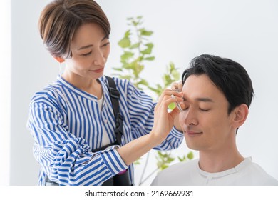 Cosmetologist And Japanese Man Trimming Eyebrows
