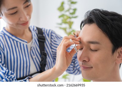 Cosmetologist And Japanese Man Trimming Eyebrows
