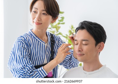 Cosmetologist And Japanese Man Trimming Eyebrows
