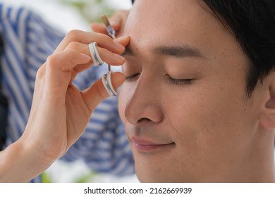 Cosmetologist And Japanese Man Trimming Eyebrows
