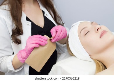 A Cosmetologist In Latex Gloves Opens A Sealed Sterile Package With A Set Of Tools.