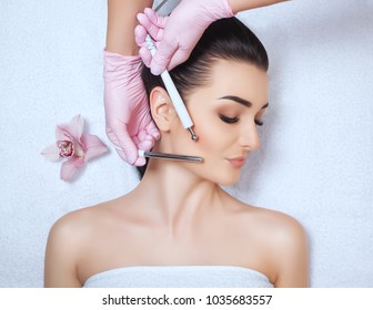 The cosmetologist makes the apparatus a procedure of Microcurrent therapy of a beautiful, young woman in a beauty salon. Cosmetology and professional skin care. - Shutterstock ID 1035683557