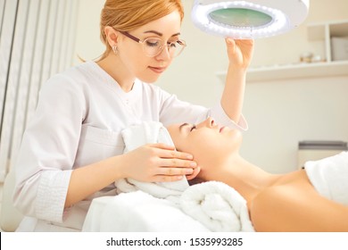 A cosmetologist makes a face mask to a patient