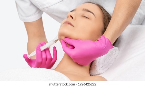 Cosmetologist makes lipolytic injections to burn fat on the chin, cheeks and neck of a woman against double chin. Female aesthetic cosmetology in a beauty salon.Cosmetology concept.