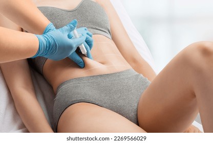 cosmetologist makes lipolytic injections to burn fat on the stomach and waist of a woman. Female aesthetic cosmetology in a beauty salon.Cosmetology concept.