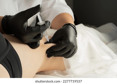 Cosmetologist makes lipolytic injections to burn fat on the stomach and waist of a woman. Dermatologist performing non invasive fat reduction procedure in beauty center. Female aesthetic cosmetology