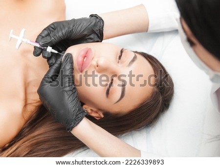 A cosmetologist makes lipolytic injections to burn fat on a woman's chin against a double chin. Women's aesthetic cosmetology in a beauty salon.The concept of cosmetology.