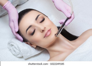 The cosmetologist makes the procedure Microdermabrasion of the facial skin of a beautiful, young woman in a beauty salon.Cosmetology and professional skin care.