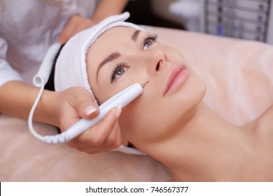 The cosmetologist makes the procedure treatment of Couperose of the facial skin of a beautiful, young woman in a beauty salon.Cosmetology and professional skin care.