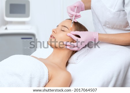 Cosmetologist makes rejuvenating anti wrinkle injections on the face of a beautiful woman. Female aesthetic cosmetology in a beauty salon.