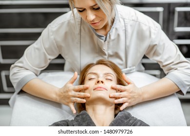 Cosmetologist Making Facial Massage To A Beautiful Woman At The Beauty Salon. Concept Of A Lymph Drainage Therapy