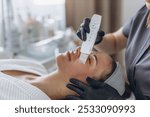 Cosmetologist making facial treatment with ultrasonic spatula to young woman. . High quality photo