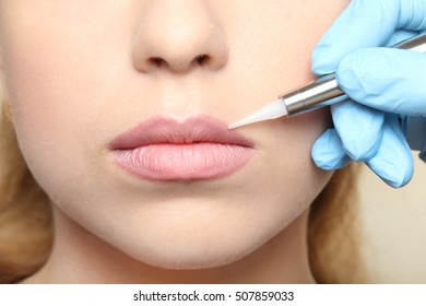 Cosmetologist making permanent make up on lips, close up