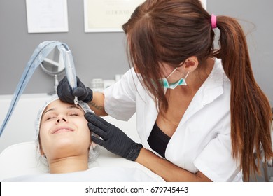 Cosmetologist making permanent makeup on woman's face