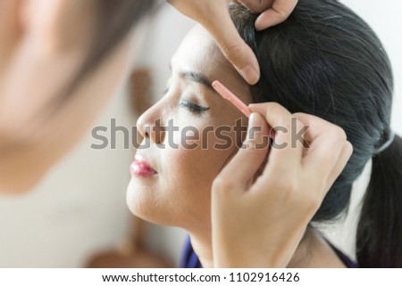 Cosmetologist making permanent makeup on face woman's, woman plucking eyebrows depilating with tweezers.