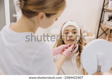 Cosmetologist marking precise injection points on a young woman's face, preparing for a botox treatment in a professional clinic setting