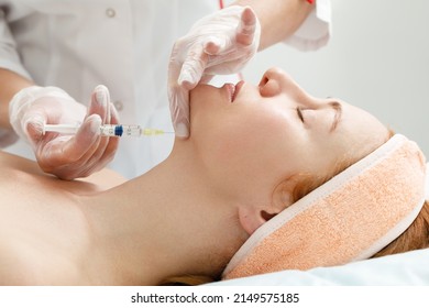 Cosmetologist performs the chin lift procedure by injecting beauty injections. Doctor injecting hyaluronic acid into the ching of a woman as a facial rejuvenation treatment.