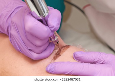 A cosmetologist performs permanent makeup. Inserting pigment with a needle.