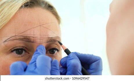 Cosmetologist preparing woman for eyebrow permanent makeup procedure, closeup