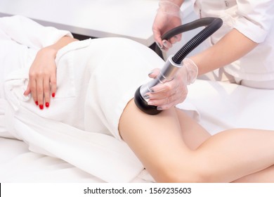 Cosmetologist reducing cellulite on the hips of a female patient, using ultrasound cavitation machine. Cropped shot of a woman getting rf lifting treatment on the back of her legs