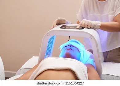 Cosmetologist setting LED lamp for color light therapy