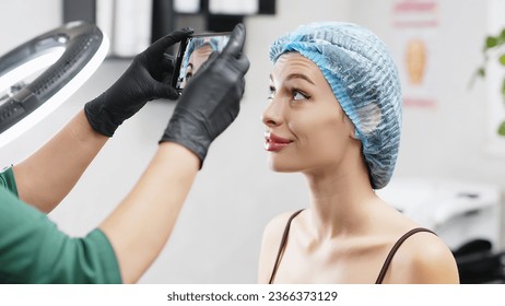 A cosmetologist-doctor marks with a pen the injection site of Botox into the forehead of a beautiful patient. The concept of preparing for an injection of a beautiful, young woman. - Powered by Shutterstock