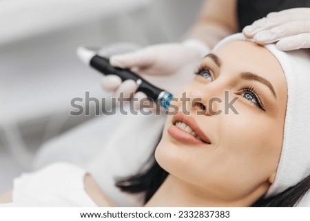 Cosmetology clinic. Professional female cosmetologist doing hydrafacial procedure while being a work. Attractive nice woman lying on the medical bed while having beauty procedures