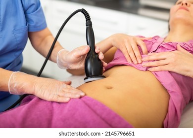 Cosmetology doctor makes a young female client lying on the couch a vacuum massage of the abdomen with the study of ..problem areas by lifting. Close-up image - Shutterstock ID 2145796651