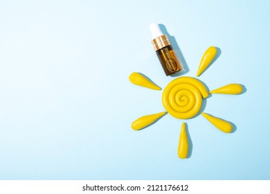 Cosmetology Product For Facial Care. Serum In Glass Bottle With Pipette And Yellow Plasticine Modeling Clay Sun On Blue Background. Essential Oil For Care With Spf. Skin Care, Moisturizing Beauty 