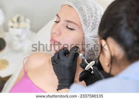 cosmetology specialist expertly uses filler syringe on client's jowls. patient undergoing comprehensive facial therapy aimed at reducing masseter lines and refining face contours, anti-aging treatment