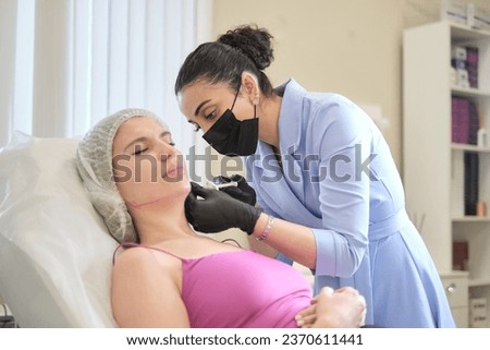cosmetology specialist expertly uses filler syringe on client's jowls. patient undergoing comprehensive facial therapy aimed at reducing masseter lines and refining face contours, anti-aging treatment