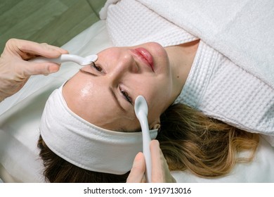 Cosmetology. A Young Beautiful Woman Gets A Facial Massage With Porcelain Spoons Around Her Eyes At The Beauty Institute. Beauty Salon. Beauty Treatments.