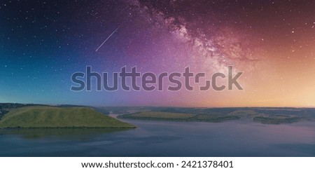 Cosmic night sky over a calm river and green hills, with the Milky Way and a shooting star visible. Bakota, Dnister river, Ukraine. Quiet travel concept. Beauty of earth.