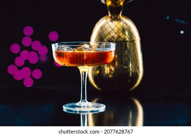 Cosmopolitan cocktail glass on the table with the blurred vibrant fluorescent lights in the dark background