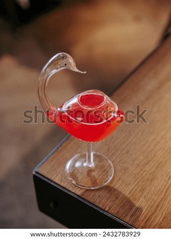 Cosmopolitan cocktail in swan bird glass, minimalistic aesthetic photo on bar counter edge. Popular alcoholic cosmopolitan cocktail made with vodka, triple sec, cranberry juice, lime juice. Bar menu