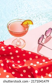 Cosmopolitan. Cold Drink On A Hot Summer Day. Cocktail Glass Near Swimming Pool Over Blue Sky Background. Vacation, Happiness, Summer Vibes And Ad Concept. Vintage Retro Style