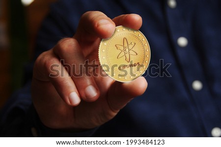 Cosmos atom cryptocurrency symbol golden coin in hand abstract concept.