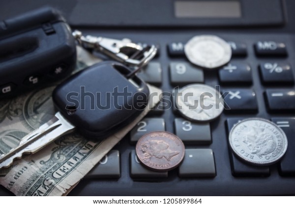 The cost of the\
car, the rise in gasoline prices, expensive maintenance. Keys and\
coins lie on the background of the calculator. The background is\
blurred.