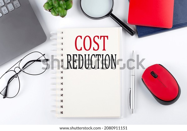 COST REDUCTION text on notepad with laptop on\
the white background