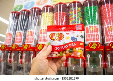 Costa Mesa, California/United States - 09/22/2019: A Hand Holds A Package Of Jelly Belly Jelly Beans In Front Of A Dispenser Of Jelly Belly Jelly Beans At The Grocery Store.