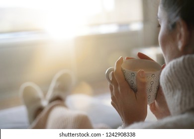 Cosy brunette at home on couch with hot drink