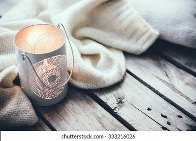 Cosy And Soft Winter Background, Knitted Sweater And Candles On An Old Vintage Wooden Board. Christmas Holidays At Home.