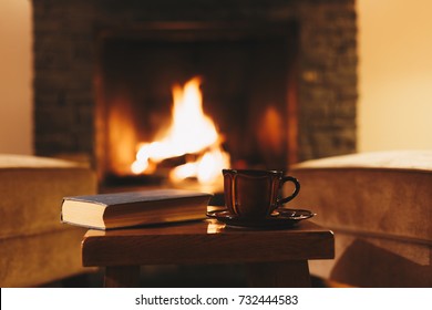 Cosy Winter Evening In Mountain Chalet. Cup Of Hot Drink In Front Of Fireplace