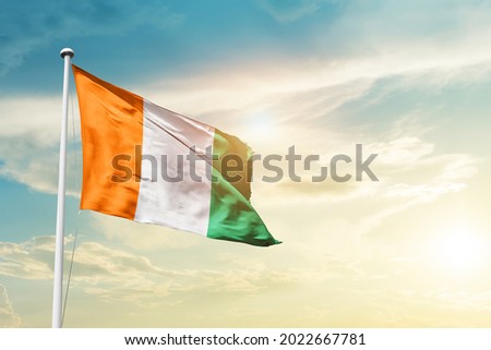Cote d Ivoire national flag waving in beautiful clouds.