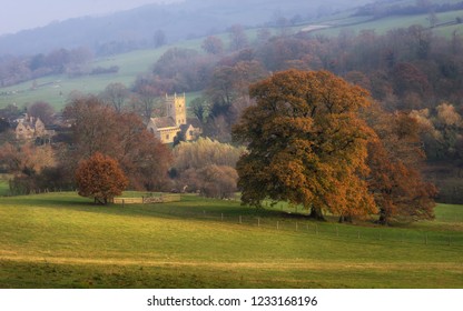 Cotswolds St. Eadburgha's Church In Autumn Nestled In Early Morning Sunlight