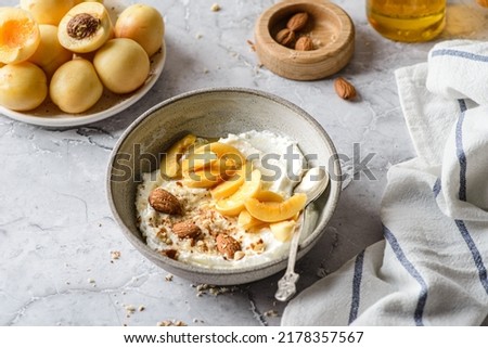 cottage cheese with apricots and almonds. Cottage cheese is in a bowl on the table in the sunlight, next to a plate with apricots and nuts, and honey