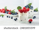 Cottage cheese with cream, raspberries, and blueberries garnished with fresh mint. 