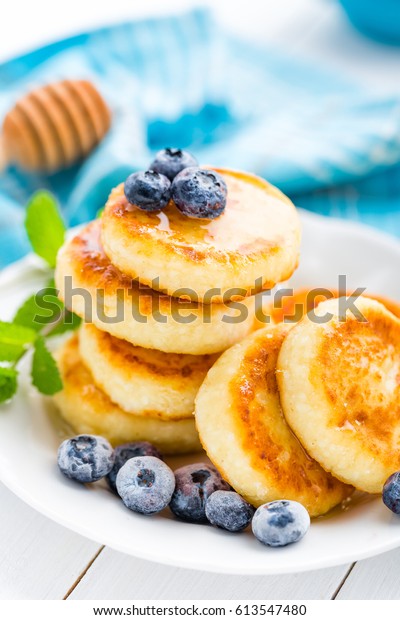 Cottage cheese pancakes with honey and blueberry on white background, breakfast or lunch