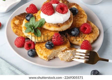 Cottage cheese pancakes with raspberries and blueberry on light background, breakfast or lunch